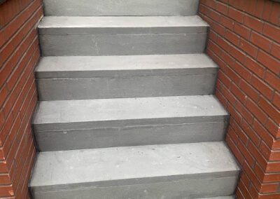 A flight of gray concrete steps flanked by red brick walls.